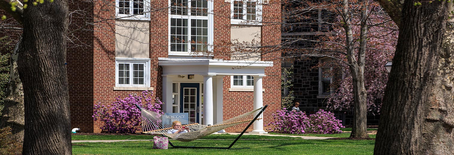 A student lounges on a hammock in front of Monocacy Hall.