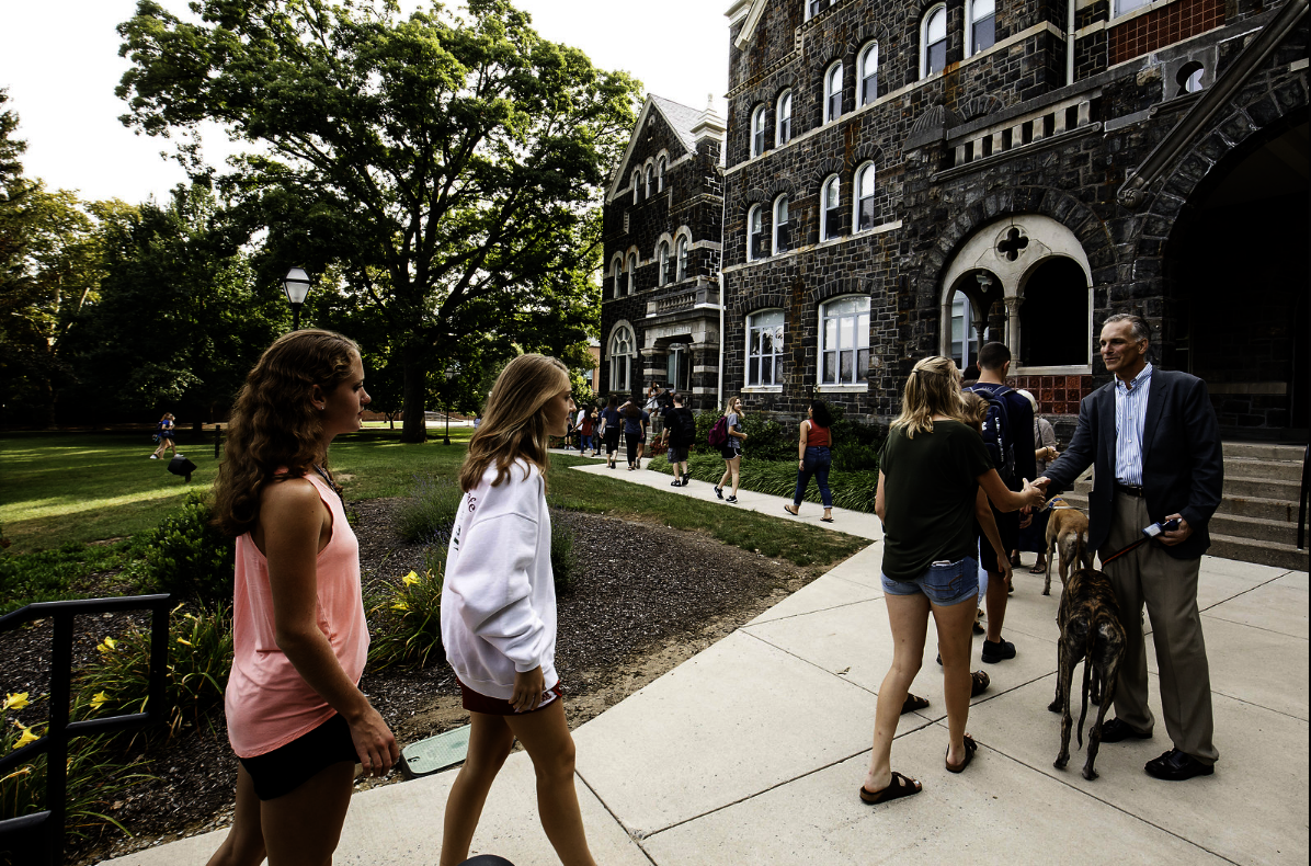 President Grigsby with his two Great Danes, Moe and Benny, greet students in the front of Comenius Hall as they walk along the path.