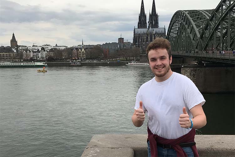 Moravian student gives two thumbs up by the river in Erfurt Germany.
