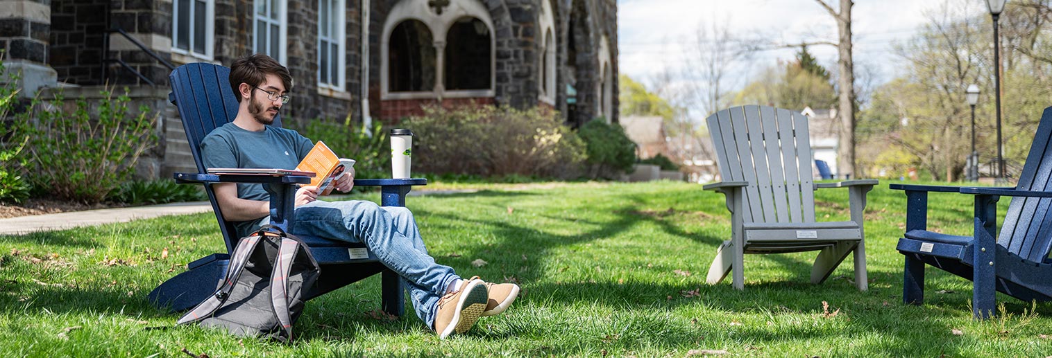 Student sitting in chair on lawn