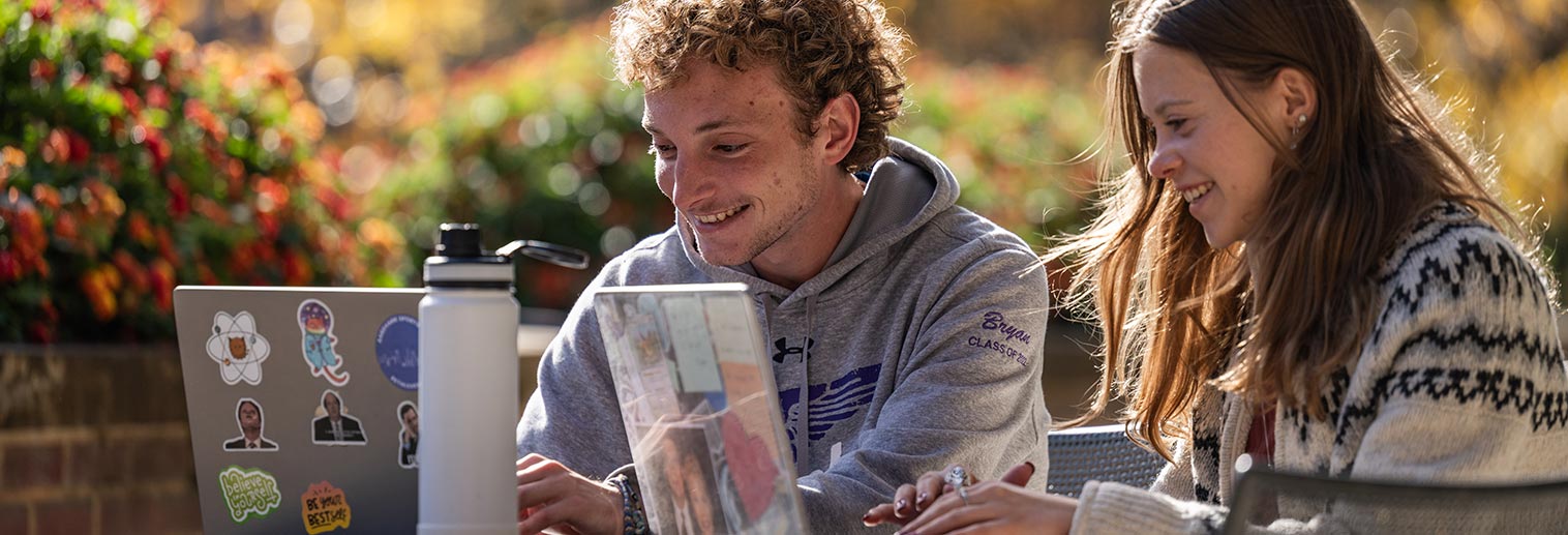 Students sitting outside with laptops