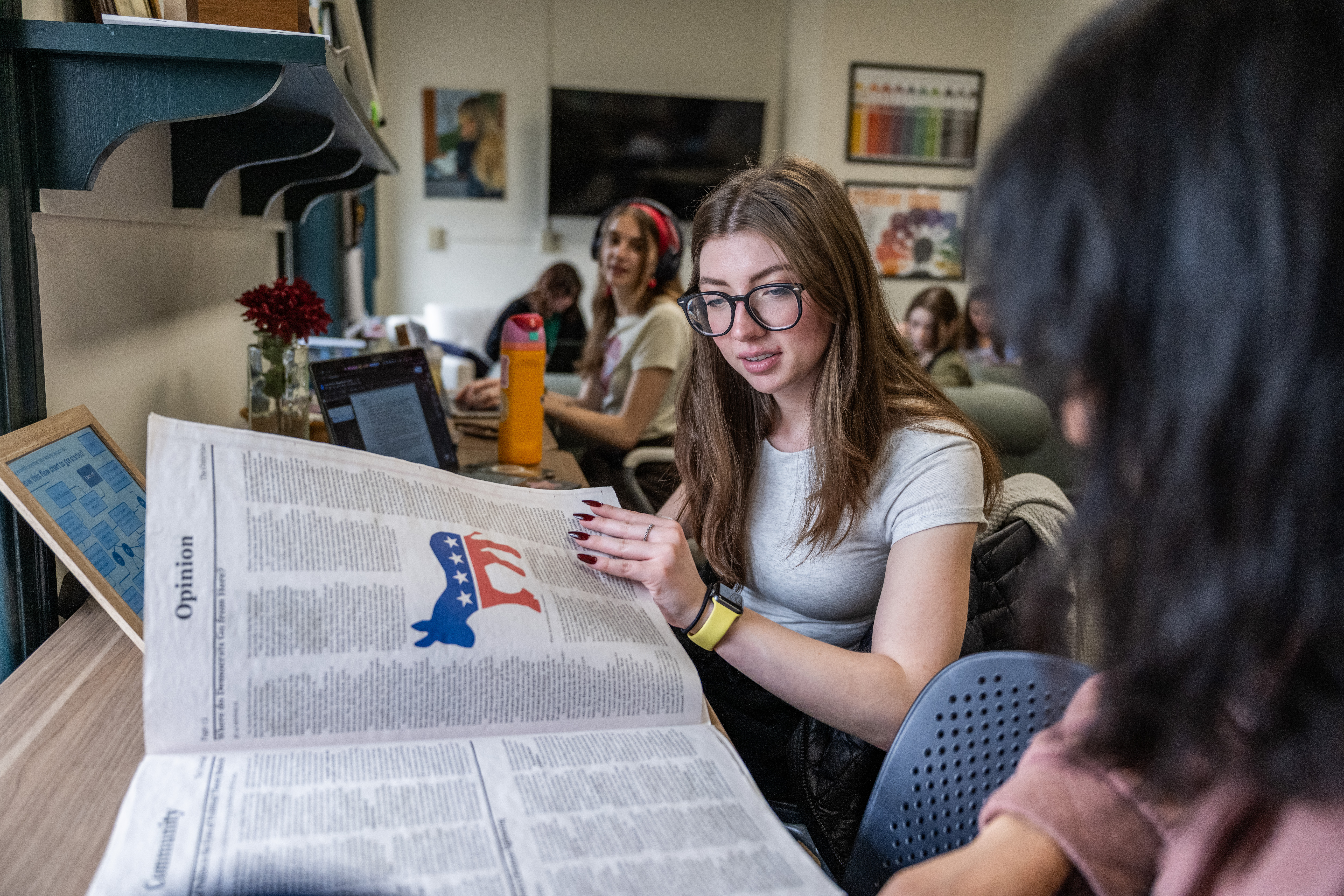 Students seated at a table in the Writing Center, looking at a copy of Moravian's student newspaper, The Comenian. 