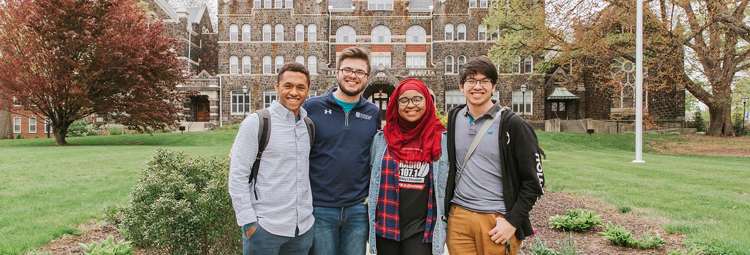 Four student standing together in front of Comenius Hall