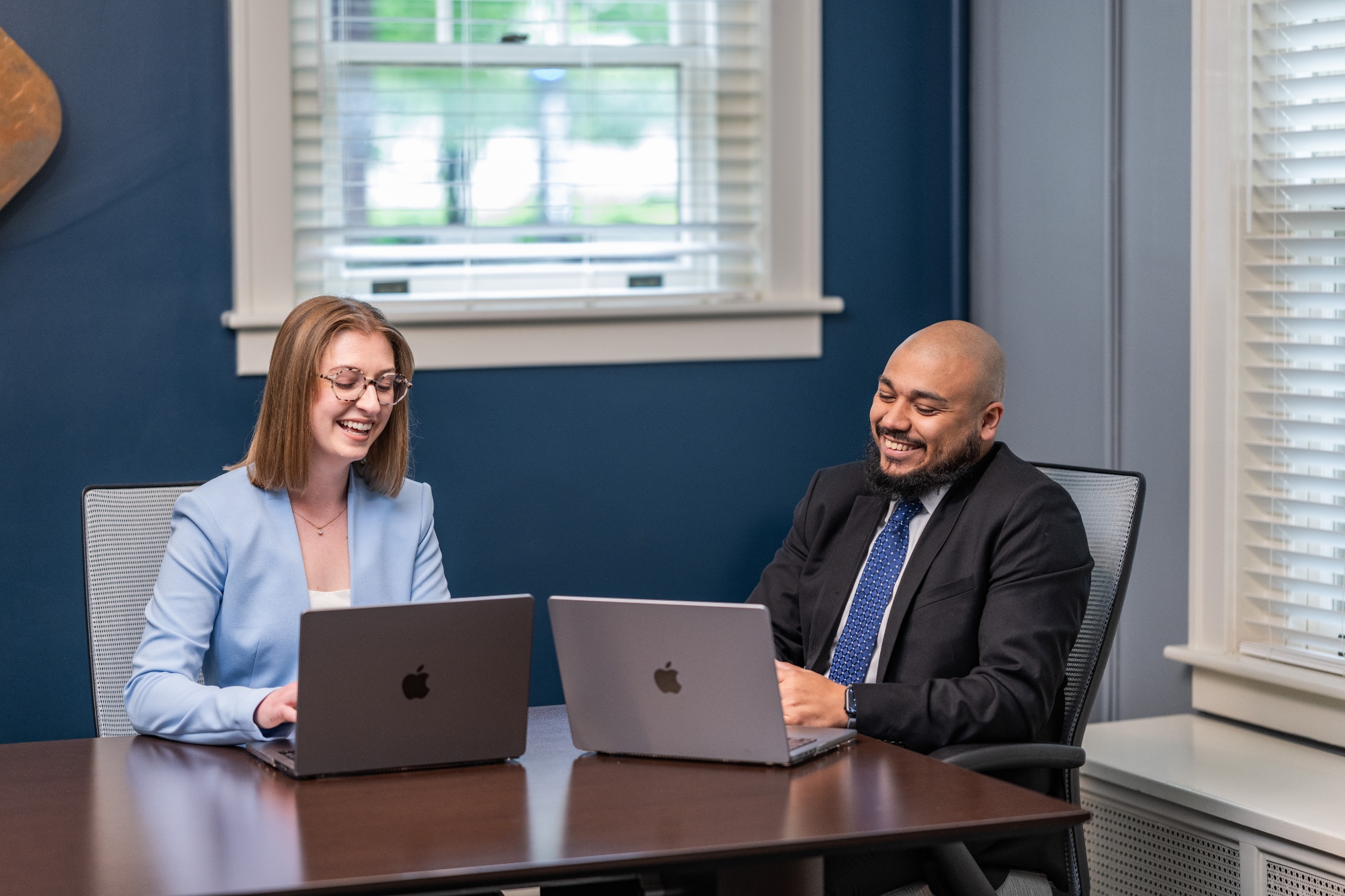 Two people at a conference table with computers open