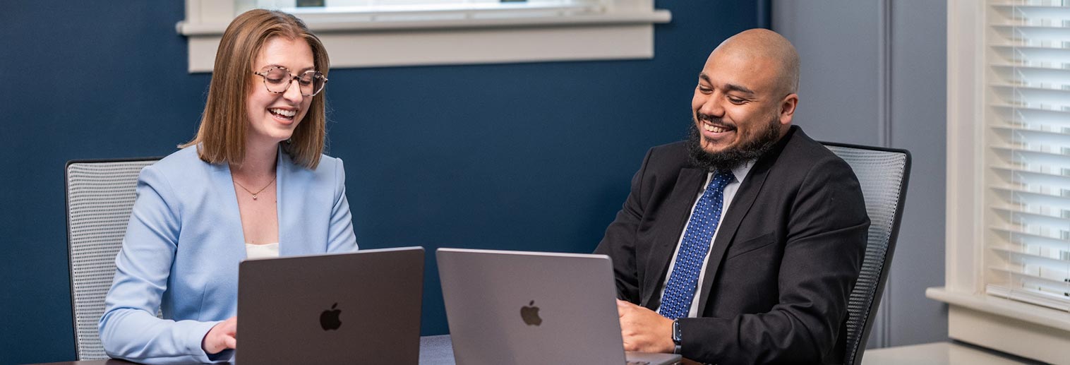 Graduate students sitting at table with laptops