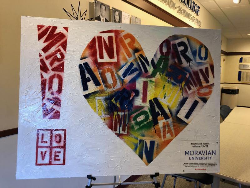 A close picture of the LOVEWESHALL Mural which features a series of multicolored letters forming the shape of a heart. On Display in the HUB building.