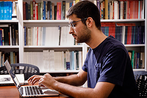 Michael works on a computer in the library.