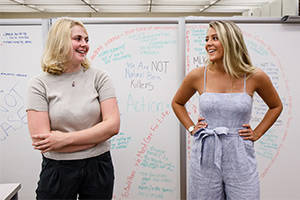 Molly and Erika stand in front of a whiteboard