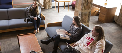 three students sitting in a residence hall lounge