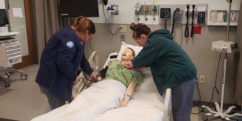 Moravian students use stethoscopes on a dummy patient.