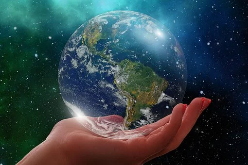 Hand holding fragile glass representation of Earth