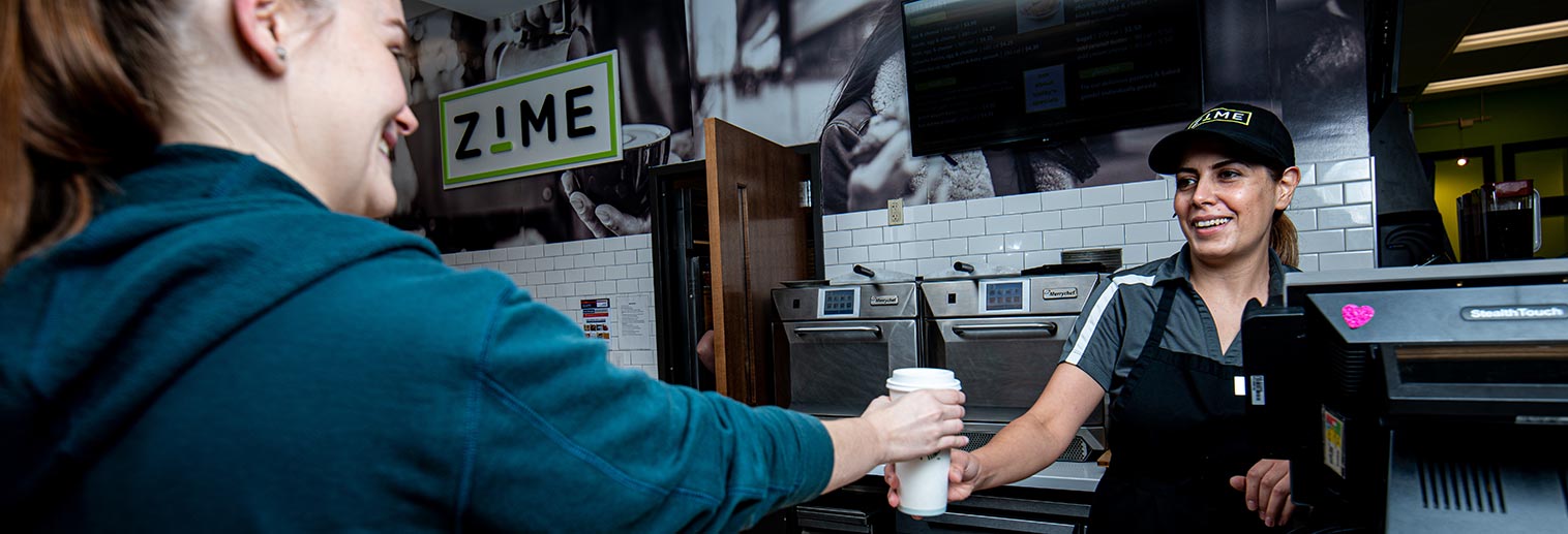 Cashier handing student a coffee in Delight's Cafe