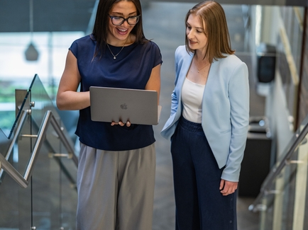 Two women on staircase looking at computer