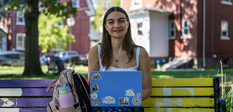 Student sitting on bench with laptop